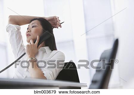 Stock Photo - Chinese businesswoman using telephone in office. Fotosearch