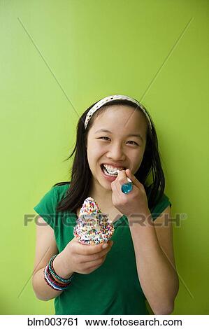 Stock Image - Chinese girl eating ice cream with sprinkles. Fotosearch