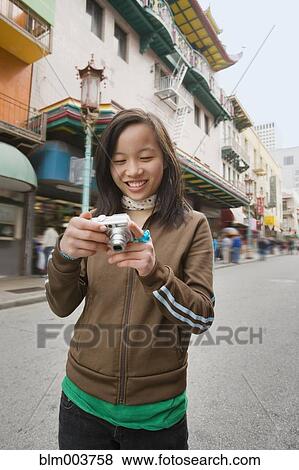 Chinese girl holding digital camera on urban street View Large Photo Image Stock Photo - Chinese girl holding digital camera on urban street. Fotosearch