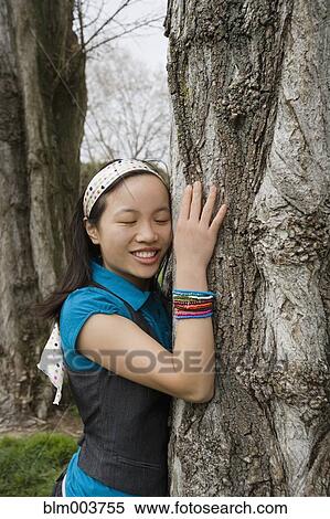 Stock Photography - Chinese girl hugging tree. Fotosearch
