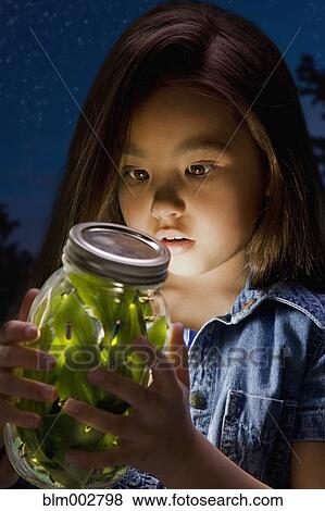 Stock Photo - Chinese girl looking at fireflies in jar. Fotosearch