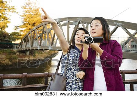 Stock Image - Chinese mother and daughter taking photographs outdoors. Fotosearch