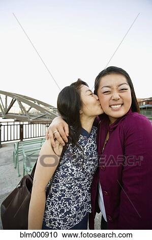 Stock Image - Chinese mother kissing daughter. Fotosearch