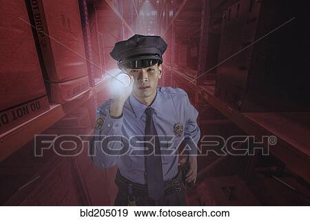 Stock Photo - Chinese police officer shining flashlight in warehouse. Fotosearch