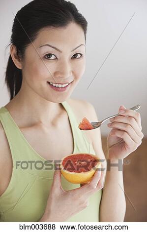 Stock Photo - Chinese woman eating grapefruit. Fotosearch