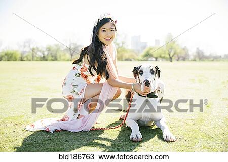 Chinese woman petting dog in field View Large Photo Image Stock Image - Chinese woman petting dog in field. Fotosearch