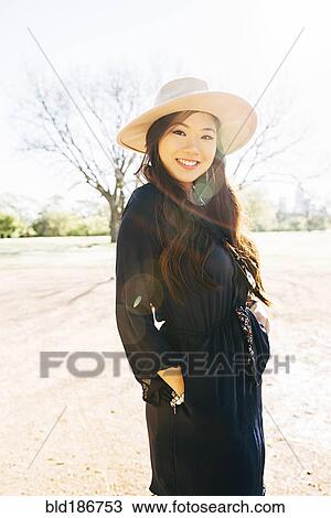 Stock Image - Chinese woman smiling in field. Fotosearch