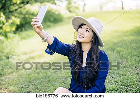 Chinese woman taking selfie in garden View Large Photo Image Stock Photograph - Chinese woman taking selfie in garden. Fotosearch