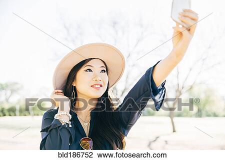 Chinese woman taking selfie outdoors View Large Photo Image Stock Image - Chinese woman taking selfie outdoors. Fotosearch