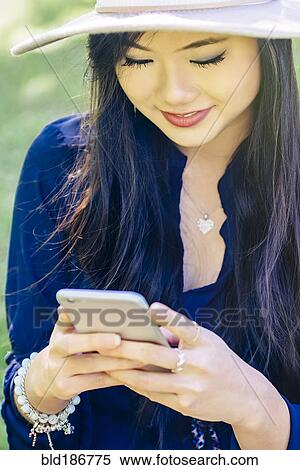 Stock Photography - Chinese woman using cell phone outdoors. Fotosearch