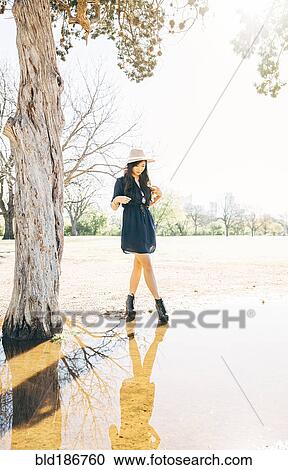 Stock Image - Chinese woman walking near pond. Fotosearch