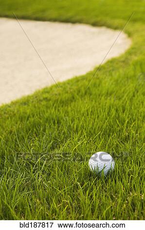Stock Photo - Close up of golf ball near sand trap on golf course. Fotosearch