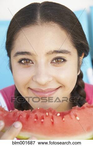 Stock Photo - Close up of Hispanic girl eating watermelon. Fotosearch