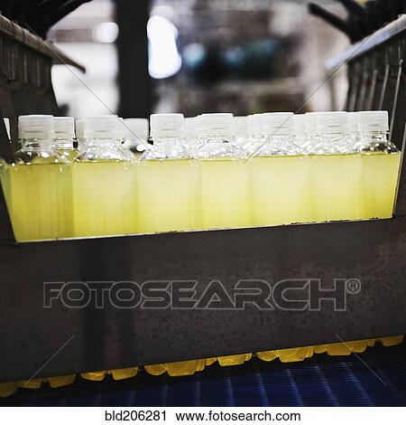 Stock Image - Close up of juice in plastic bottles on production line. Fotosearch
