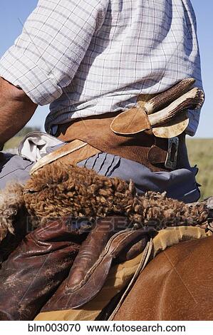 Stock Image - Close up of knife in Hispanic cowboy's waistband. Fotosearch