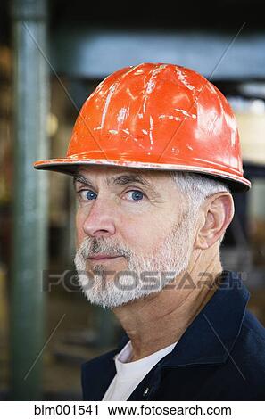Stock Image - Close up of man wearing hard hat. Fotosearch