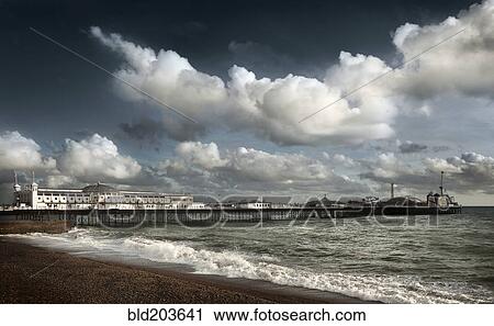 Stock Image - Clouds over boardwalk and beach, Brighton, Sussex, England. Fotosearch