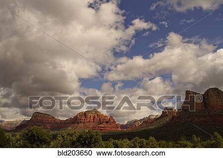 Stock Image - Clouds over rock formations in rural landscape, Sedona, AZ, United States. Fotosearch