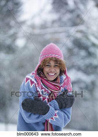 Stock Image - Cold African woman standing in the snow. Fotosearch
