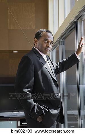 Confident African businessman leaning on glass door View Large Photo Image Stock Image - Confident African businessman leaning on glass door. Fotosearch