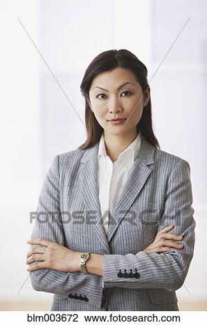 Stock Image - Confident Chinese businesswoman standing with arms crossed. Fotosearch