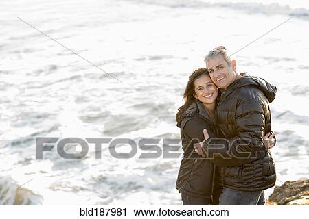 Couple hugging near ocean waves View Large Photo Image Stock Image - Couple hugging near ocean waves. Fotosearch