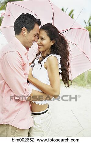 Couple hugging under umbrella View Large Photo Image Stock Image - Couple hugging under umbrella. Fotosearch