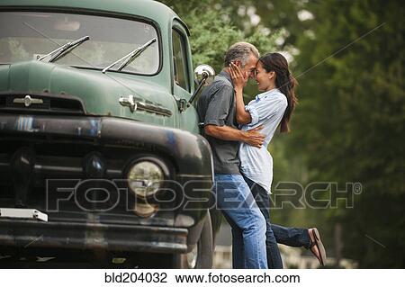 Stock Image - Couple kissing by truck outdoors. Fotosearch