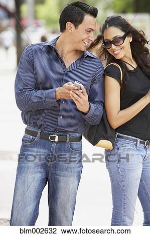 Stock Image - Couple looking at cell phone. Fotosearch