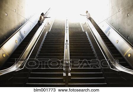 Stock Image - Couple reaching for each other across staircase. Fotosearch