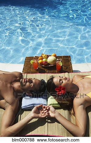 Stock Photo - Couple relaxing at edge of swimming pool. Fotosearch
