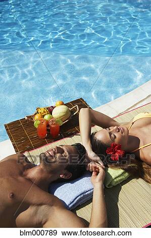 Couple relaxing at edge of swimming pool View Large Photo Image Stock Photo - Couple relaxing at edge of swimming pool. Fotosearch