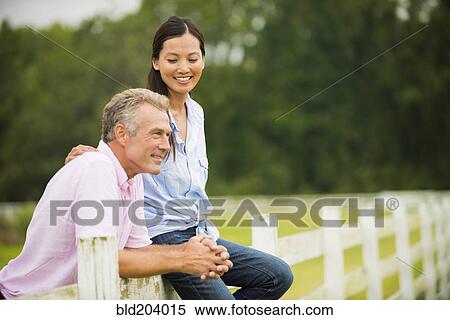 Couple relaxing together on fence View Large Photo Image Stock Photography - Couple relaxing together on fence. Fotosearch