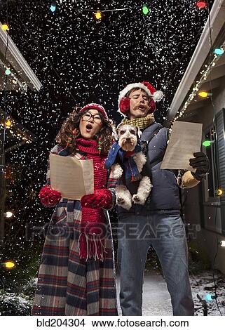 Picture - Couple singing Christmas carols with dog. Fotosearch