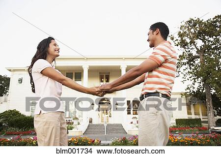 Couple smiling at each other in front of luxury home View Large Photo Image Picture - Couple smiling at each other in front of luxury home. Fotosearch