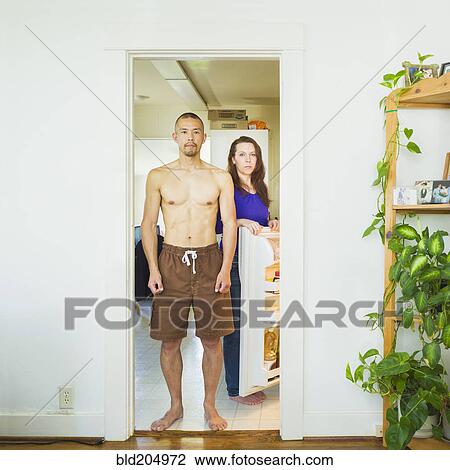 Stock Image - Couple standing in kitchen together. Fotosearch