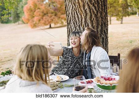 Couple taking selfie at outdoor table View Large Photo Image Stock Photo - Couple taking selfie at outdoor table. Fotosearch