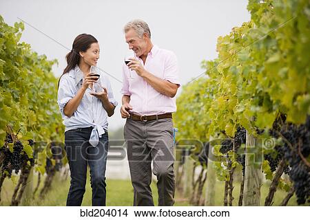 Picture - Couple tasting wine together in vineyard. Fotosearch