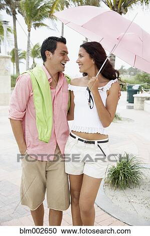 Couple walking with umbrella View Large Photo Image Stock Image - Couple walking with umbrella. Fotosearch