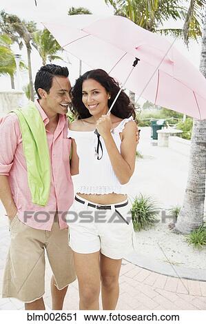Stock Image - Couple walking with umbrella. Fotosearch