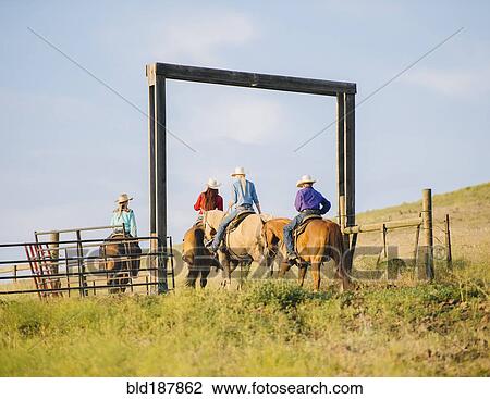 Stock Image - Cowboy and cowgirls riding horseback on ranch. Fotosearch