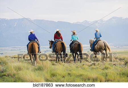 Stock Image - Cowboy and cowgirls riding horseback on ranch. Fotosearch