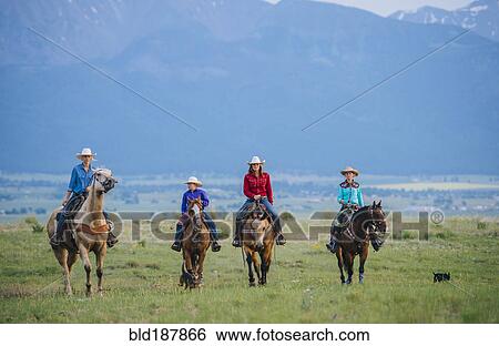 Stock Photograph - Cowboy and cowgirls riding horseback on ranch. Fotosearch