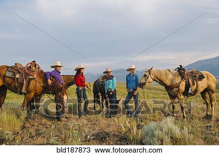 Stock Image - Cowboy and cowgirls with horses on ranch. Fotosearch