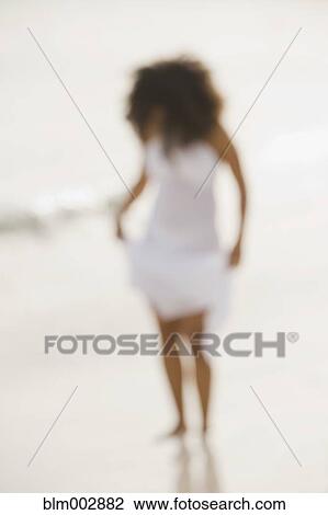 Stock Image - Defocused image of Hispanic woman at beach. Fotosearch
