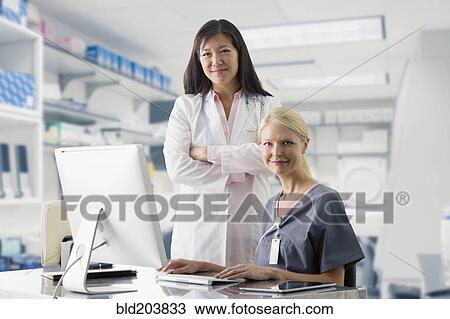 Doctor and nurse smiling at computer in hospital View Large Photo Image Stock Image - Doctor and nurse smiling at computer in hospital. Fotosearch
