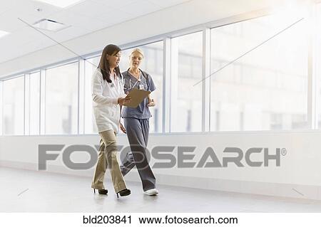 Stock Image - Doctor and nurse talking in hospital. Fotosearch