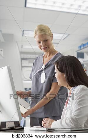 Doctor and nurse working at computer in hospital View Large Photo Image Picture - Doctor and nurse working at computer in hospital. Fotosearch