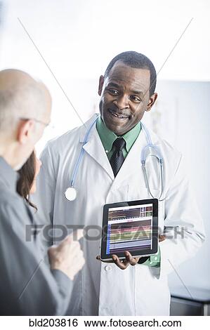 Stock Photograph - Doctor showing tablet computer to patients. Fotosearch