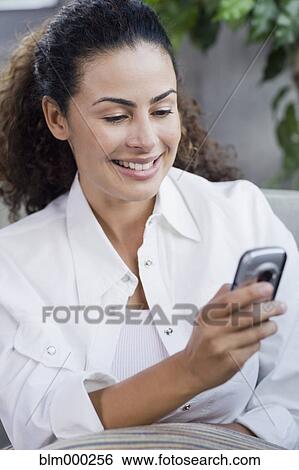 Stock Photograph - Dominican woman looking at cell phone. Fotosearch